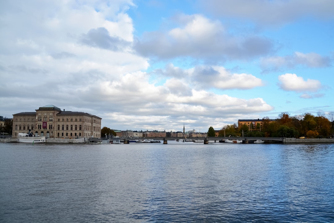 white and brown concrete building near body of water under white clouds during daytime