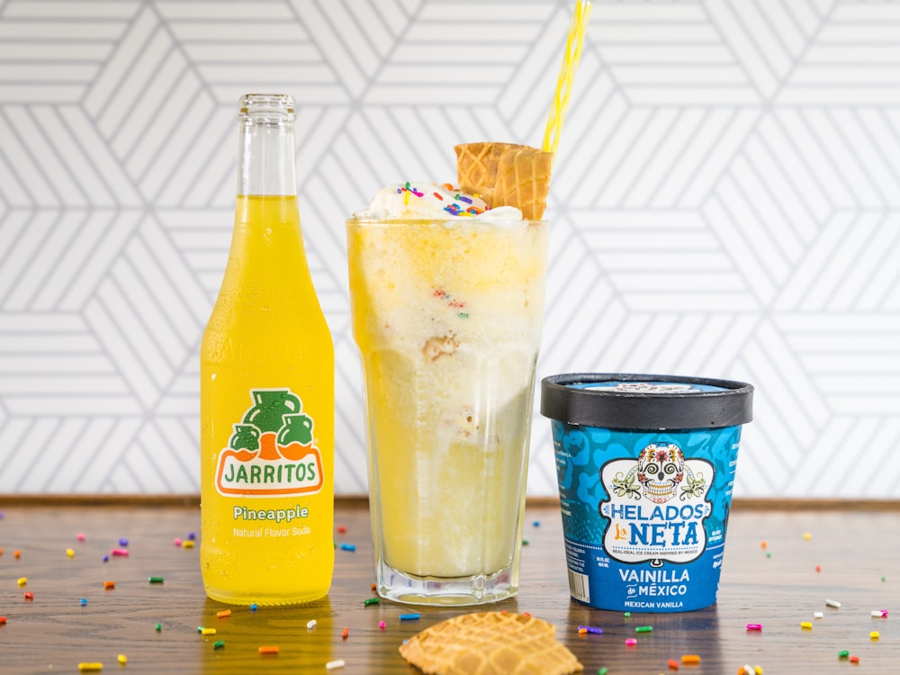 yellow liquid in clear drinking glass beside blue and white labeled bottle