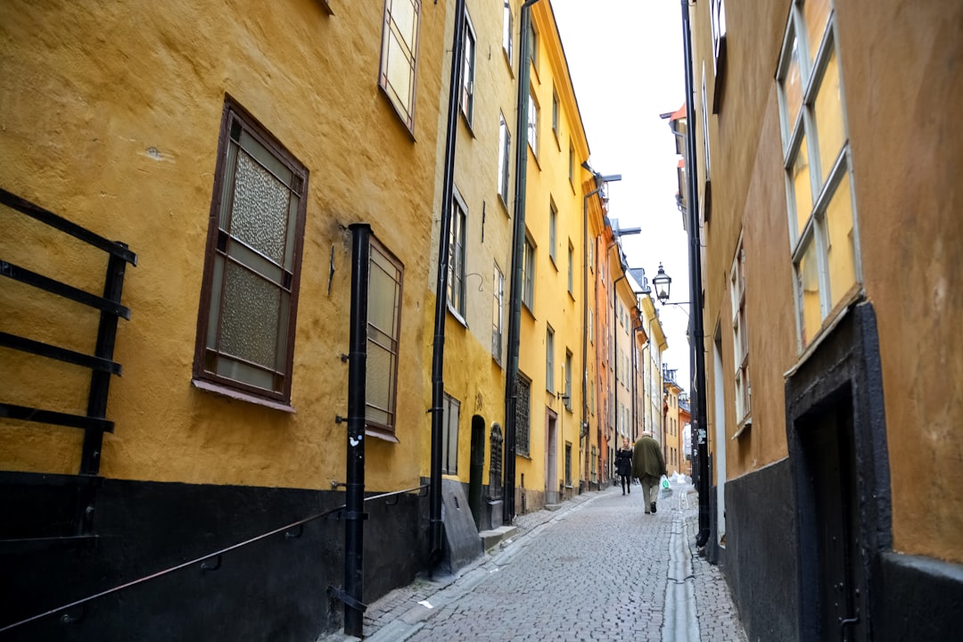 people walking on street between yellow concrete buildings during daytime