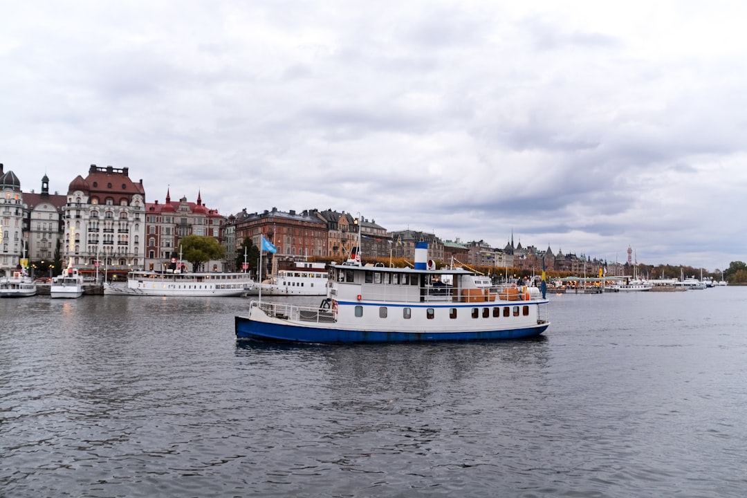 white and blue boat on water near city buildings during daytime