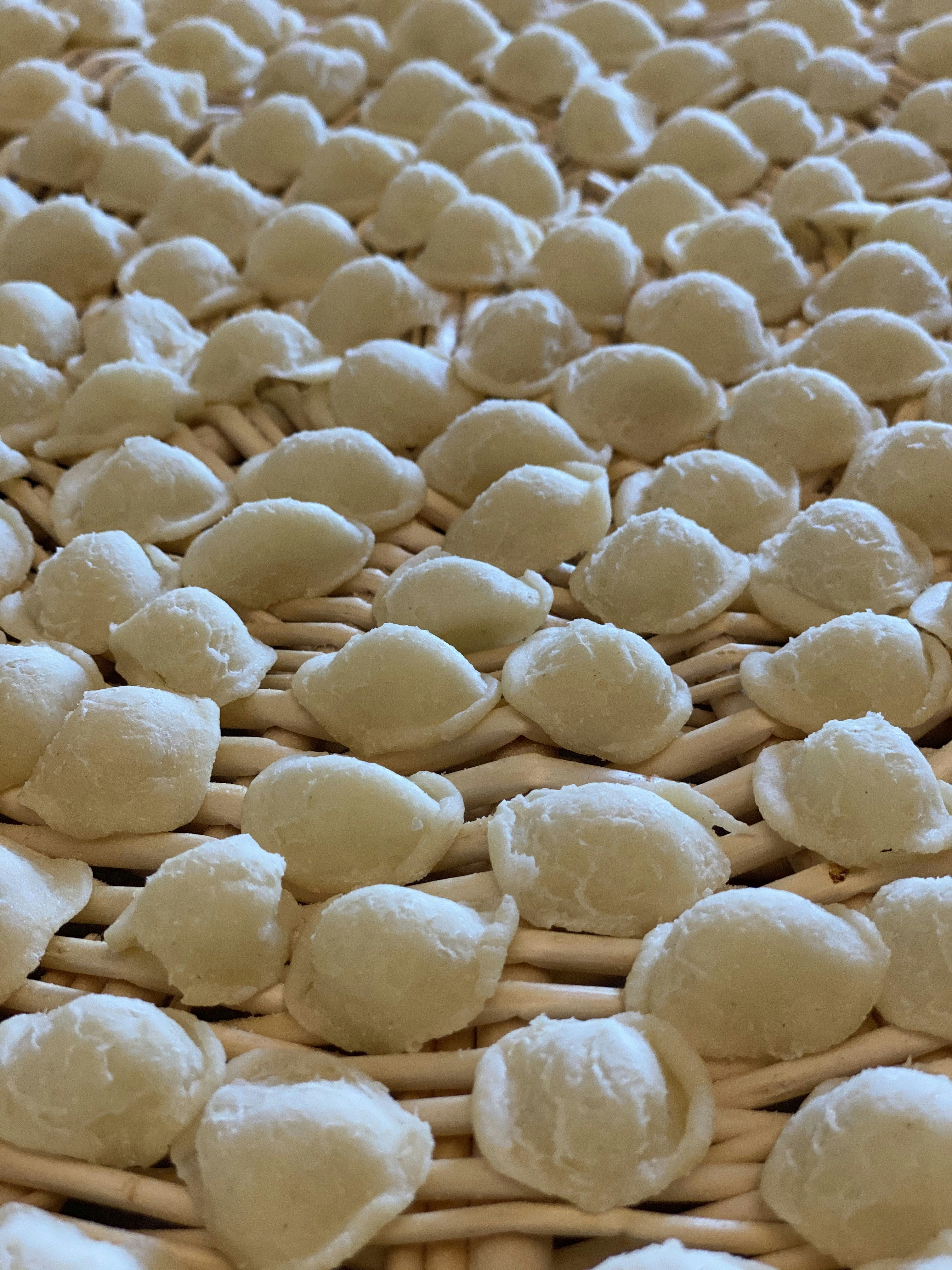 Orecchiette pasta ear-shaped pieces on a rustic linen cloth, warm afternoon light, southern Italian food photography