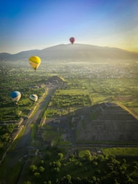 yellow hot air balloon on mid air over green grass field during daytime