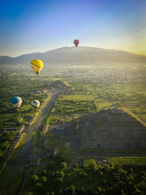 yellow hot air balloon on mid air over green grass field during daytime