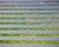 Rows of solar panels are aligned symmetrically over a green grass field, indicating a solar farm designed for harnessing solar energy.