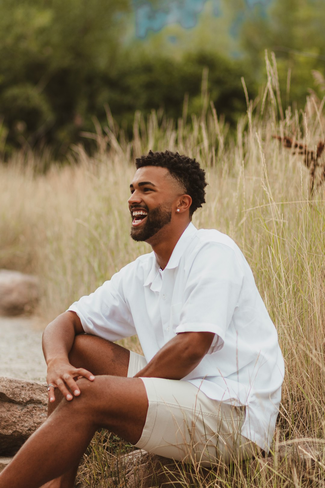 man in white polo shirt sitting on brown rock