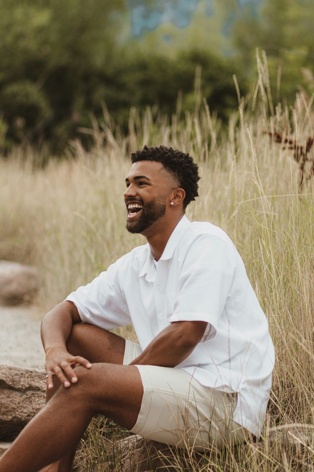 man in white polo shirt sitting on brown rock