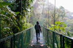 man in black jacket walking on hanging bridge