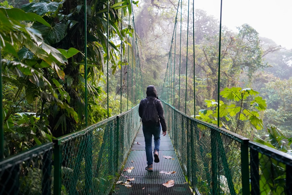 Hombre con chaqueta negra caminando en puente colgante