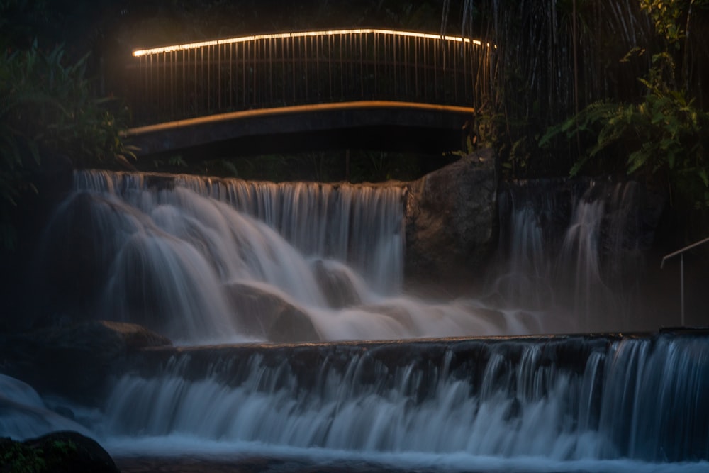 brown wooden bridge over waterfalls