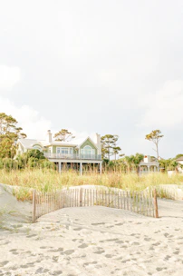 white and green wooden house surrounded by green grass field under white sky during daytime
