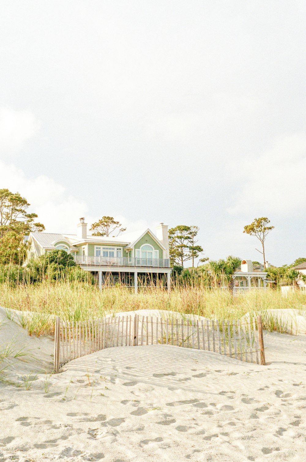 white and green wooden house surrounded by green grass field under white sky during daytime