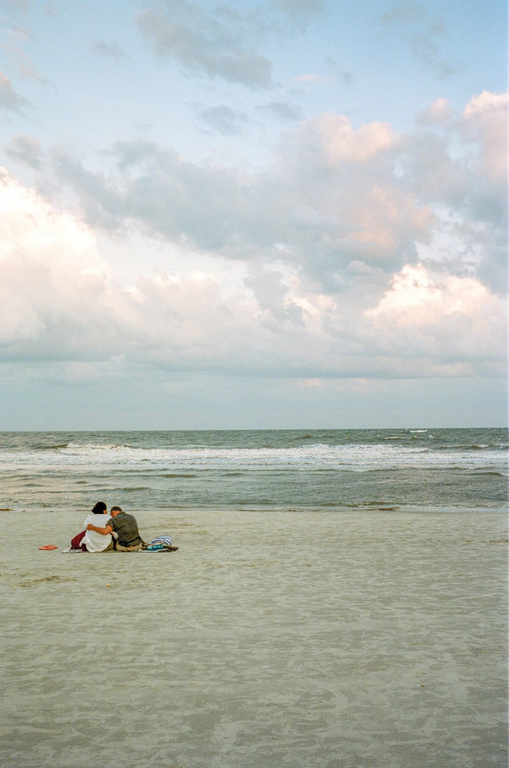 2 people sitting on blue surfboard on sea during daytime