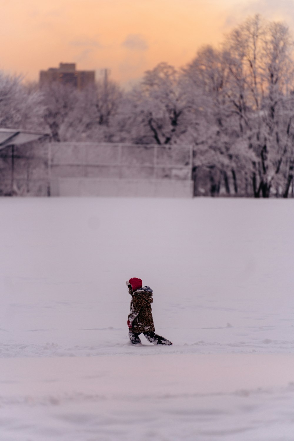 child in black jacket and black pants sitting on snow covered ground during daytime
