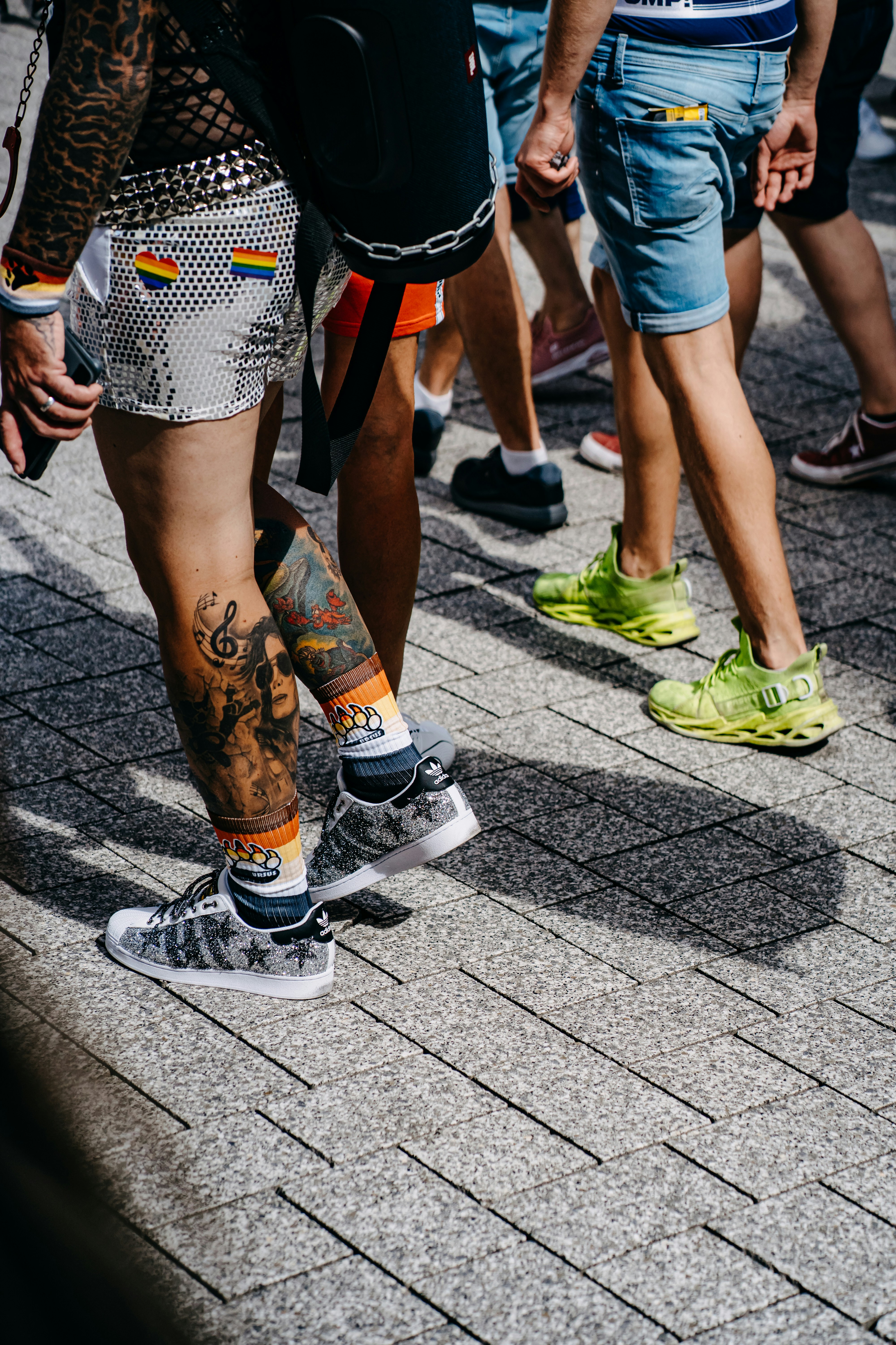 person in blue denim shorts and white sneakers walking on gray concrete pavement