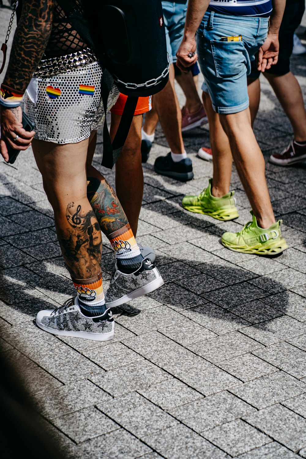 person in blue denim shorts and white sneakers walking on gray concrete pavement