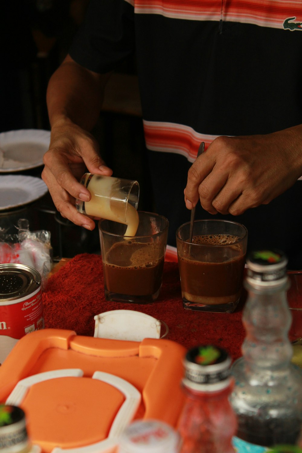 person holding clear drinking glass with brown liquid