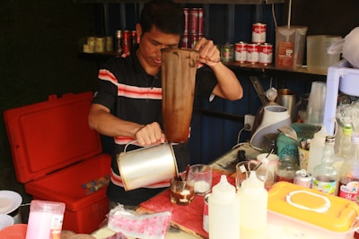 A home cook carefully preparing a specialty drink with fresh ingredients in a cozy kitchen.