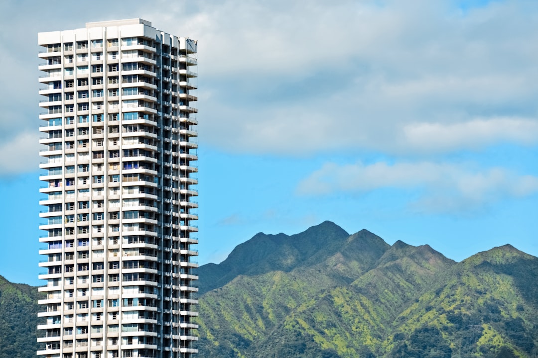 white and black concrete building near green mountain under blue sky during daytime