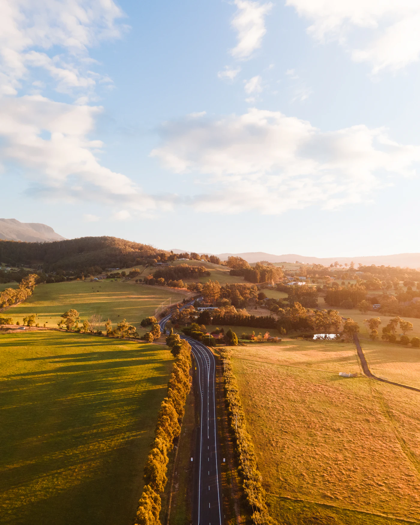 A country road through open farmland under cloud