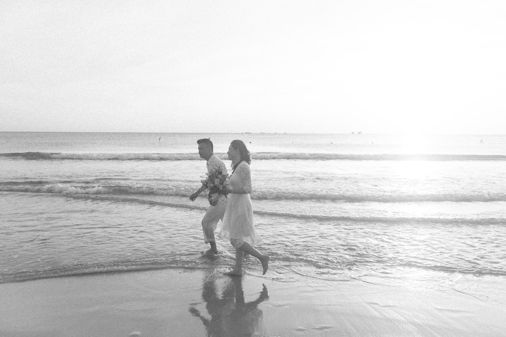 grayscale photo of 2 men and woman walking on beach