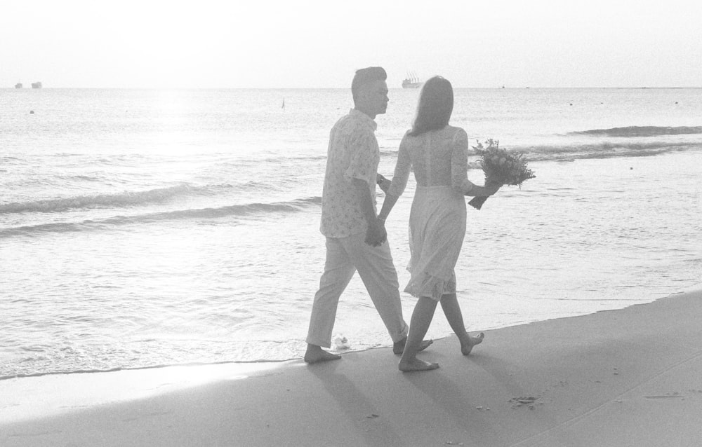 man and woman walking on beach during daytime