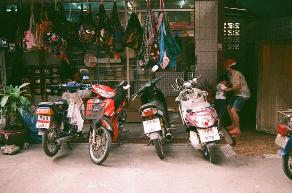 red and white motor scooter parked on sidewalk during daytime