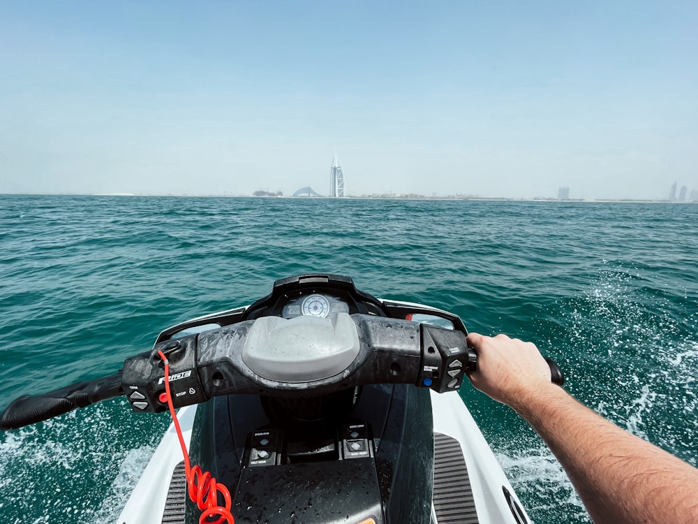 personne en gilet de sauvetage noir et rouge chevauchant un bateau blanc pendant la journée