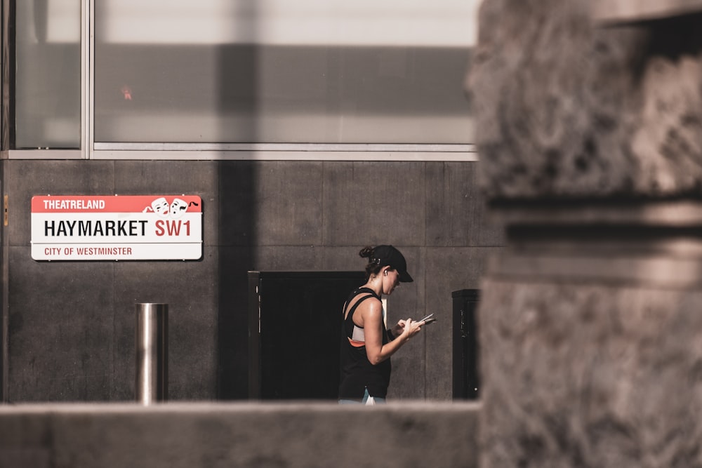 woman in black tank top and black pants sitting on concrete wall