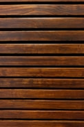 Wooden slats arranged in a horizontal pattern with a rich brown finish, showcasing the natural wood grain and texture.