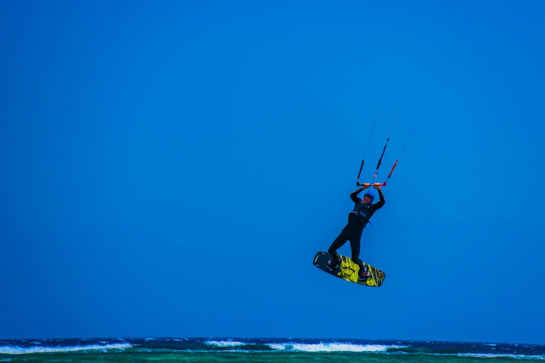 man in black and yellow wetsuit doing surfing during daytime