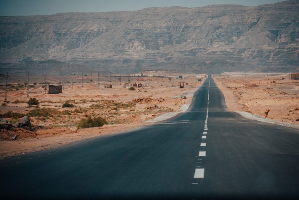 black asphalt road in the middle of brown field