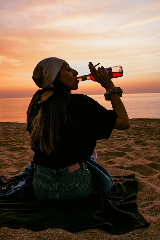 woman in black shirt drinking beer on beach during daytime in Sozopol Bulgaria