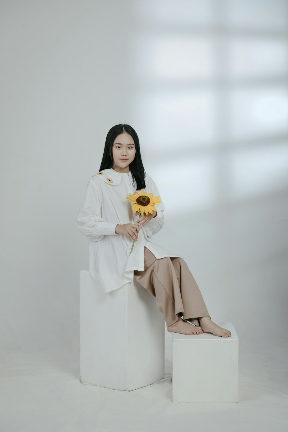 woman in brown robe holding white and yellow flower bouquet