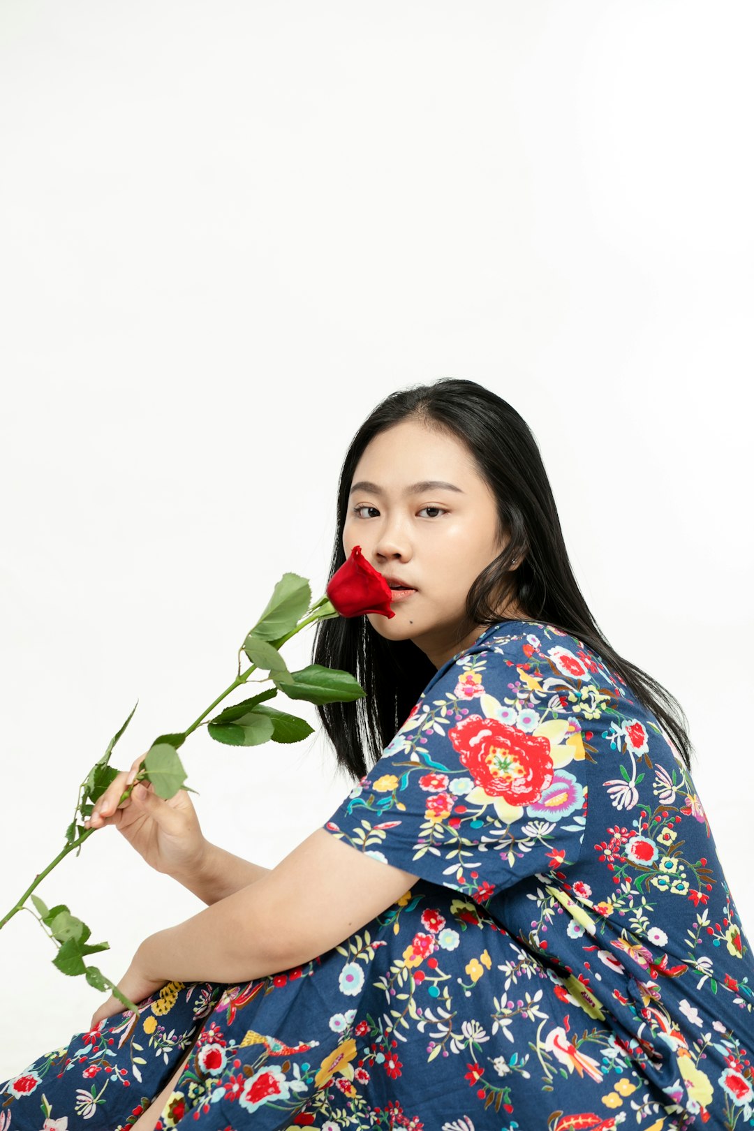 woman in blue and red floral shirt holding red rose