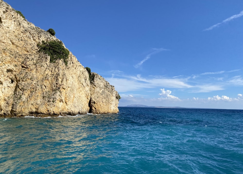 brown rock formation on sea under blue sky during daytime