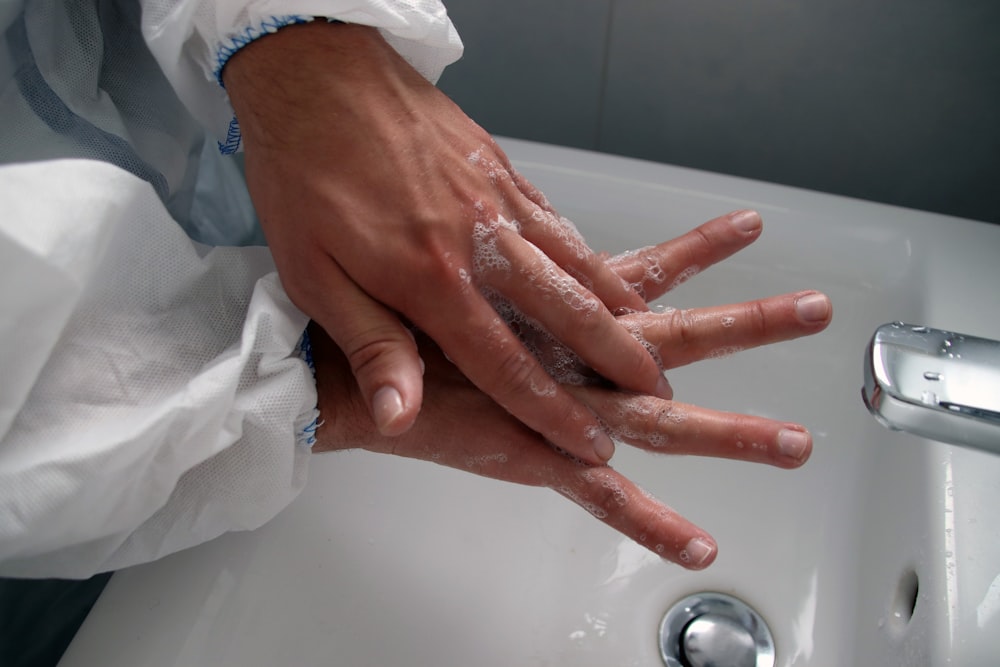 persons hand on white ceramic sink