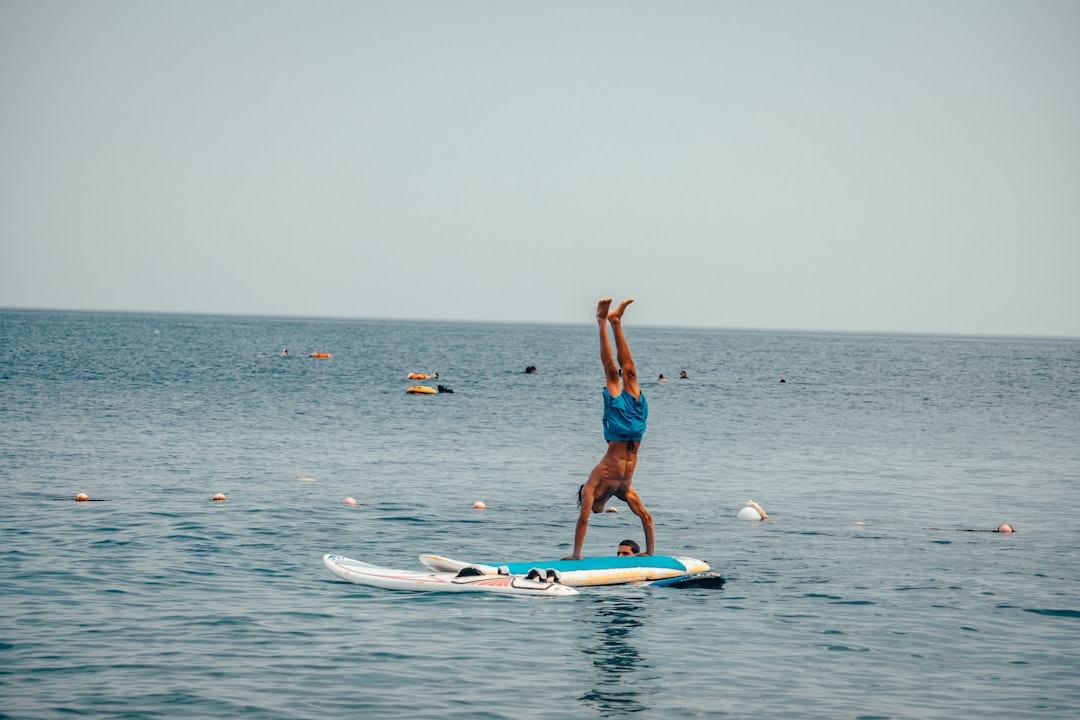 woman in blue bikini standing on white surfboard on sea during daytime