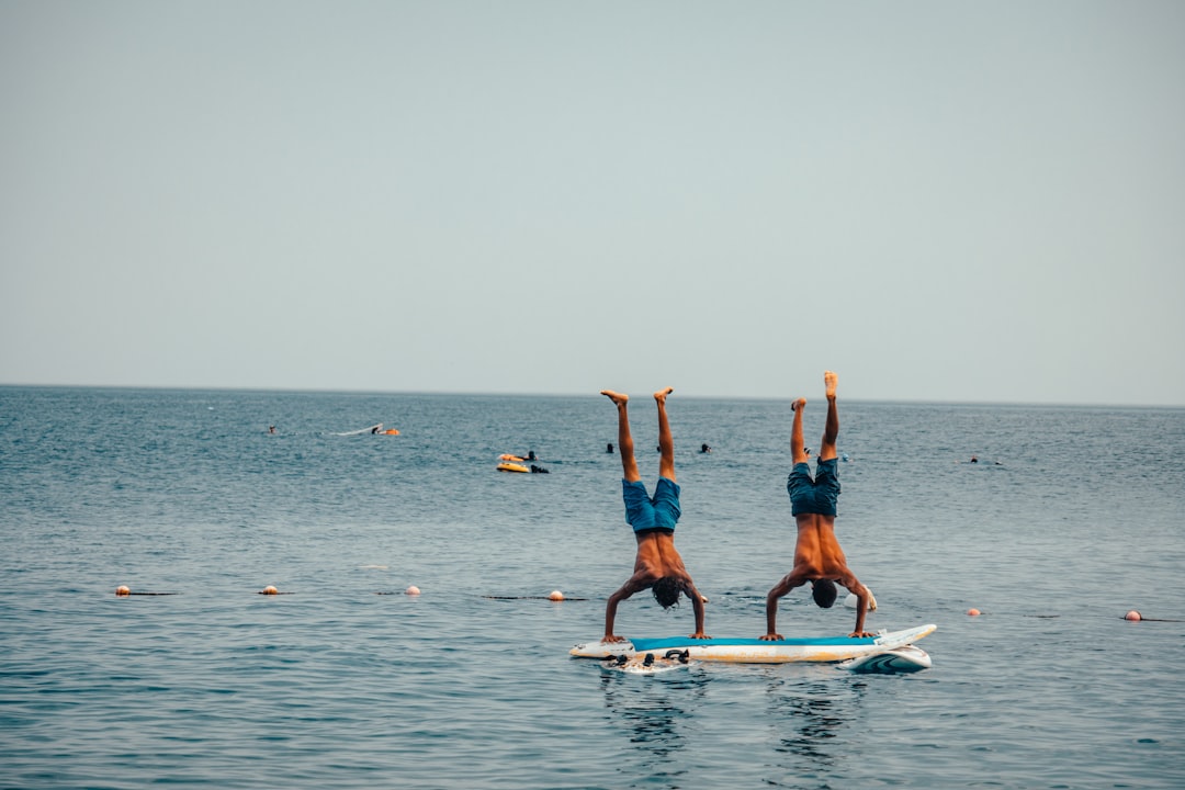 2 men and woman standing on white surfboard on sea during daytime