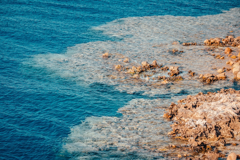 brown and white rocks on blue sea water during daytime