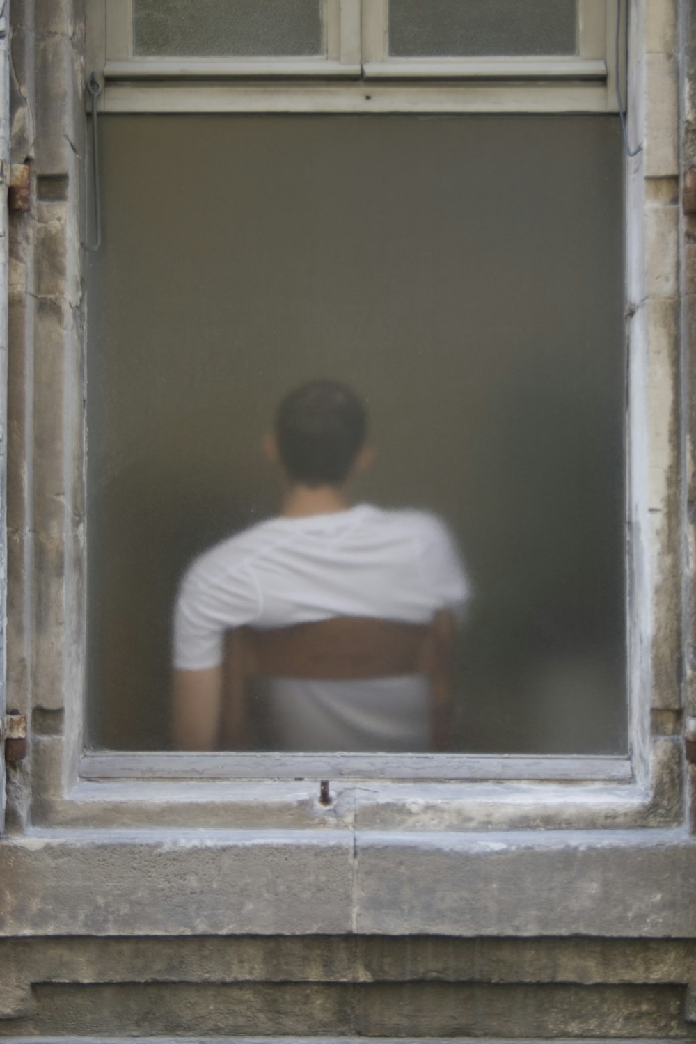man in white t-shirt sitting on window