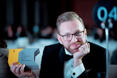 man in black suit jacket wearing eyeglasses award-winning google meet background