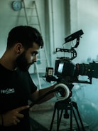man in black crew neck t-shirt holding black dslr camera