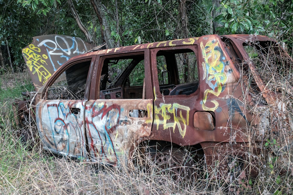 an old rusted out car with graffiti on it