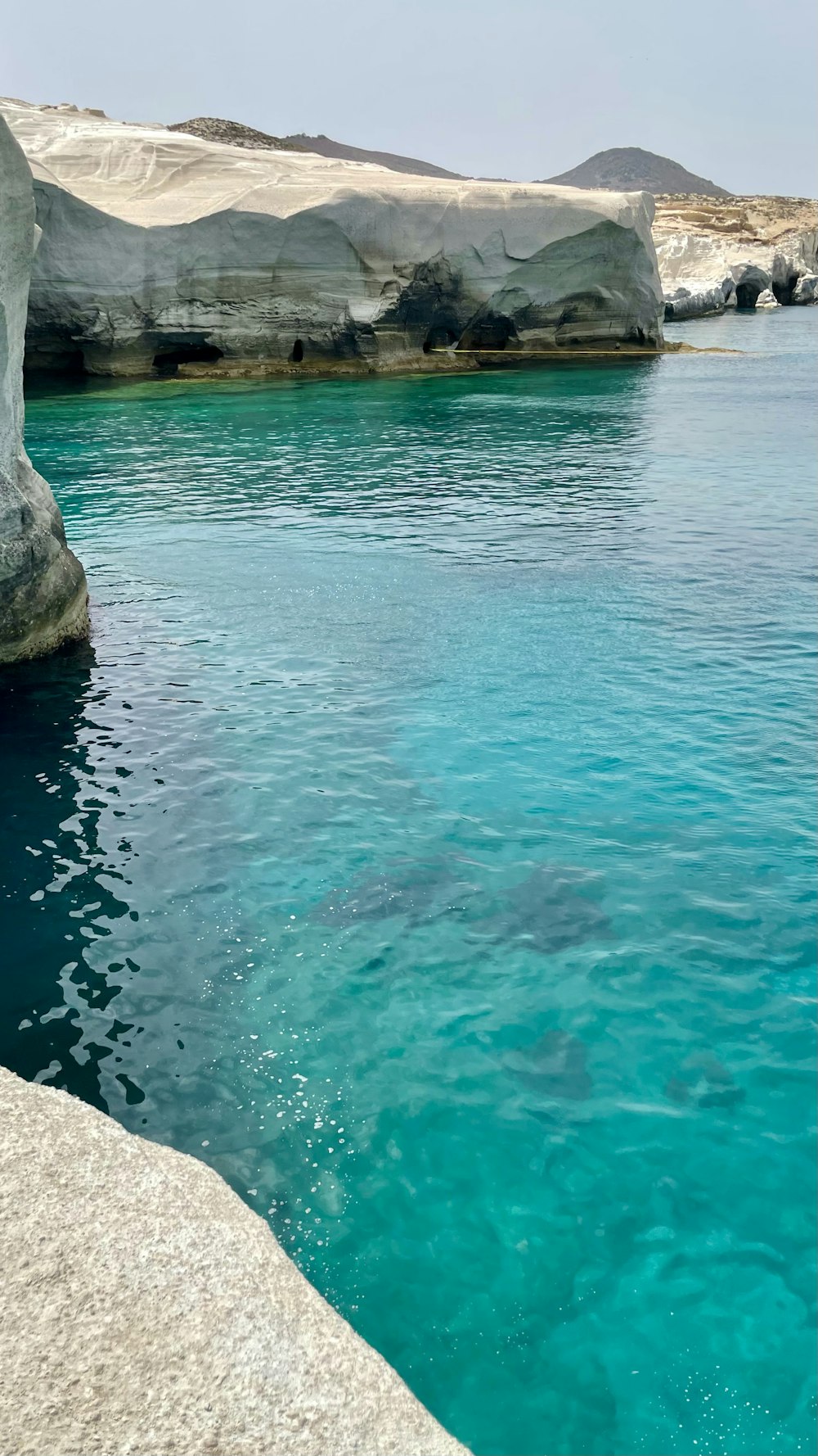 body of water near gray rock formation during daytime