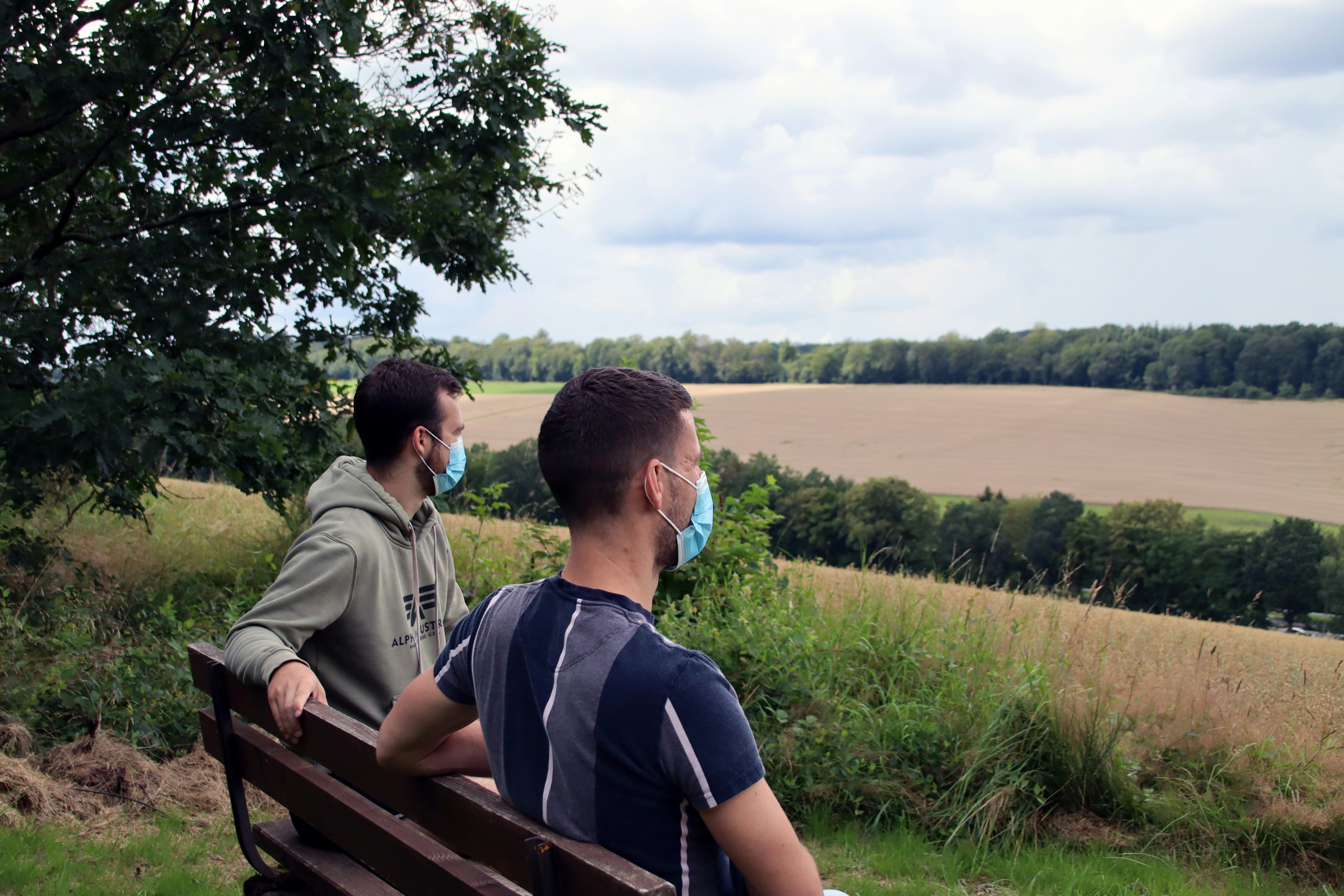 Mann im schwarzen T-Shirt tagsüber auf brauner Holzbank