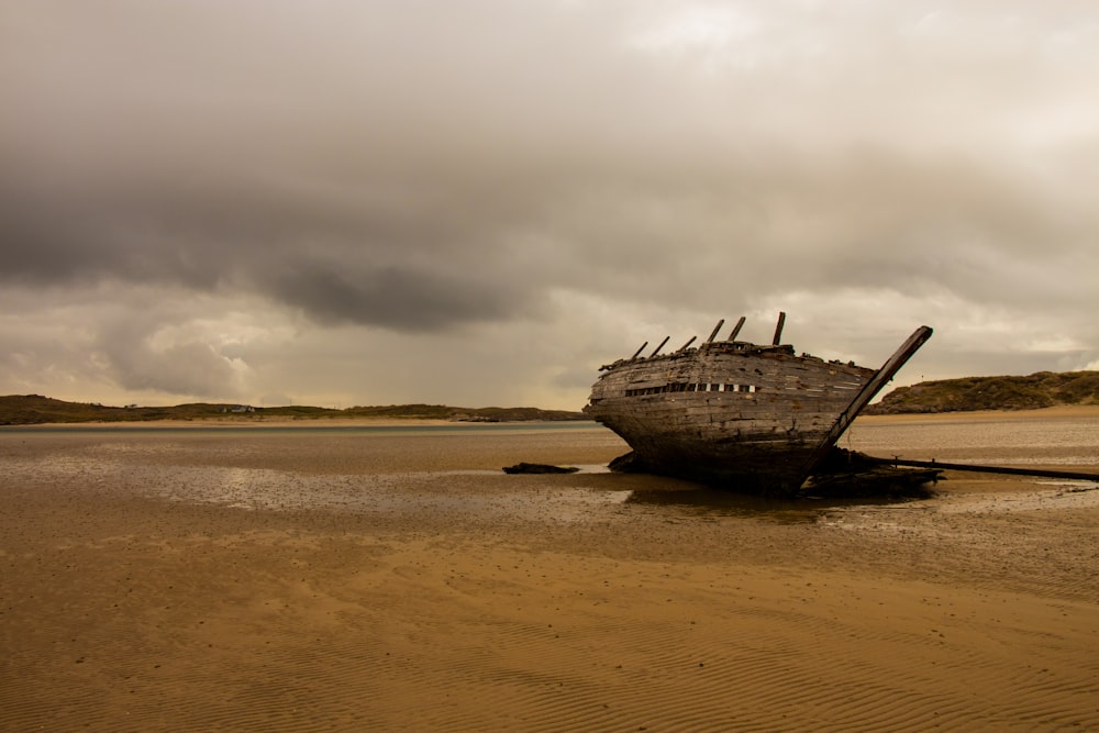 brown ship on brown sand under white clouds during daytime
