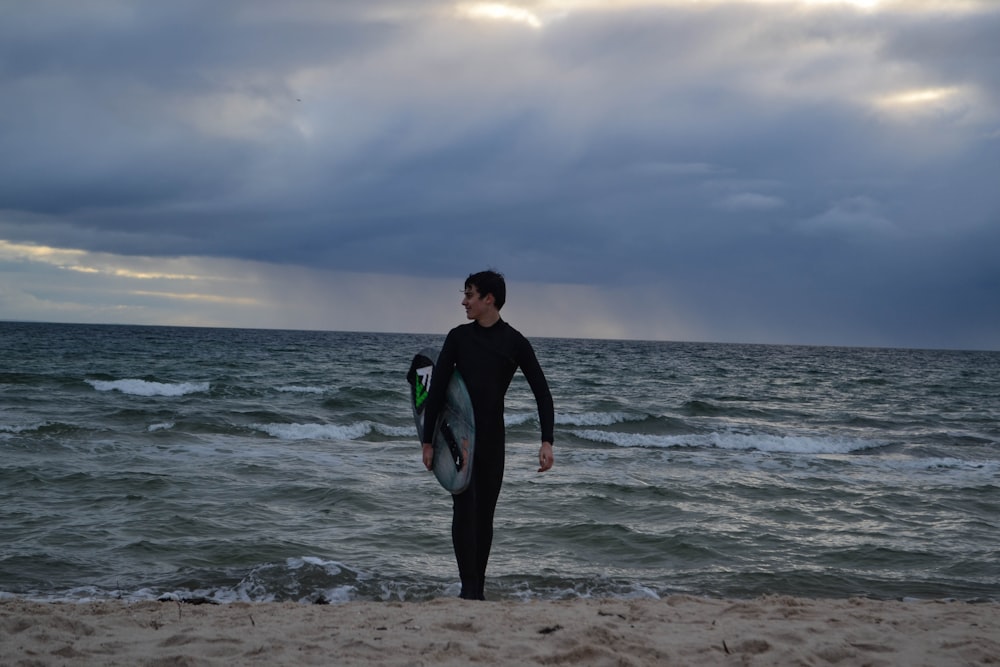 uomo in abito nero in piedi sulla spiaggia durante il giorno