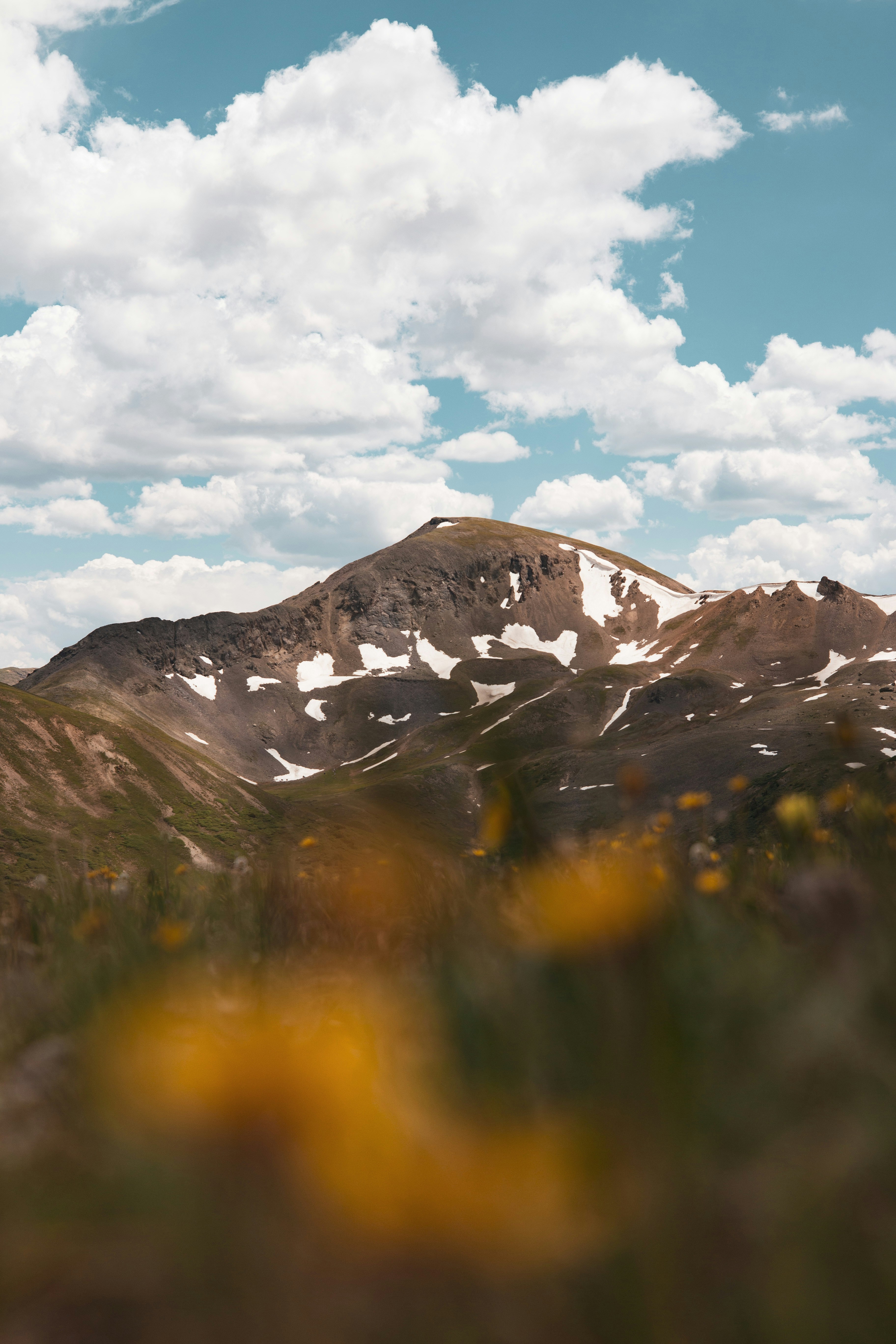 brown and white mountain under white clouds and blue sky during daytime