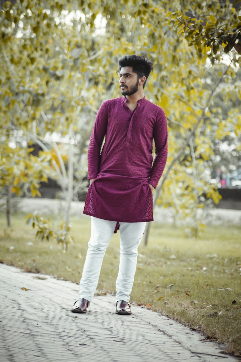 man in purple sweater and white pants standing on road during daytime