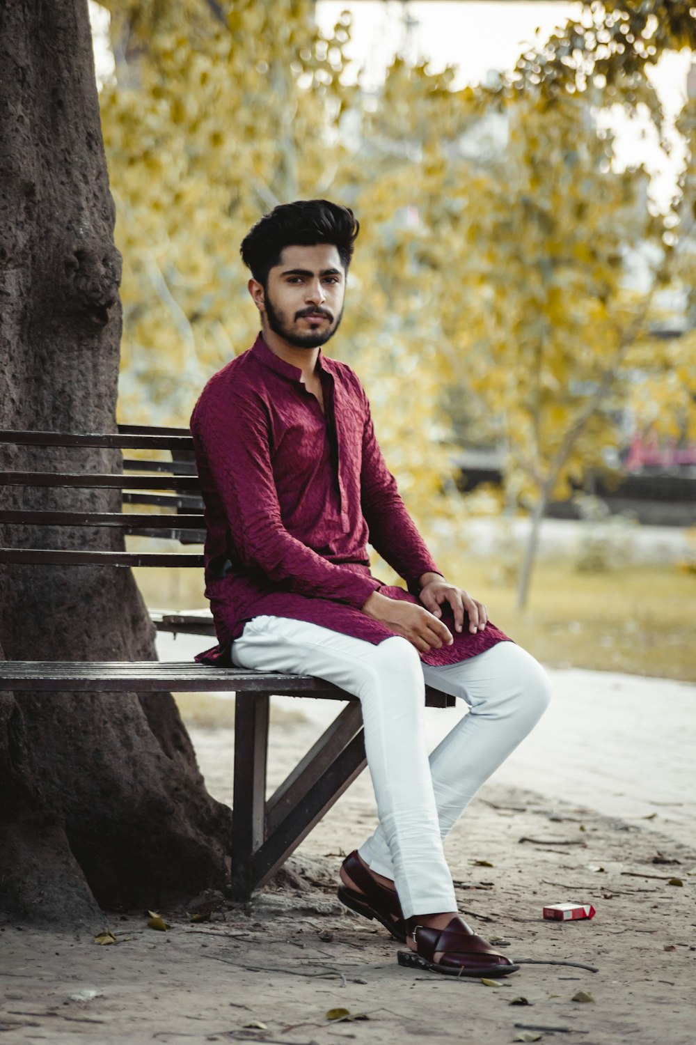 woman in red sweater and white pants sitting on brown wooden bench